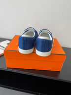 Blue denim slip-on loafers with white soles, heel backs facing outward.