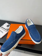 Blue denim slip-on loafers with stitched seams and white rubber outsoles.
