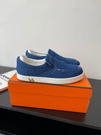 Pair of blue denim slip-on loafers with white soles on display.