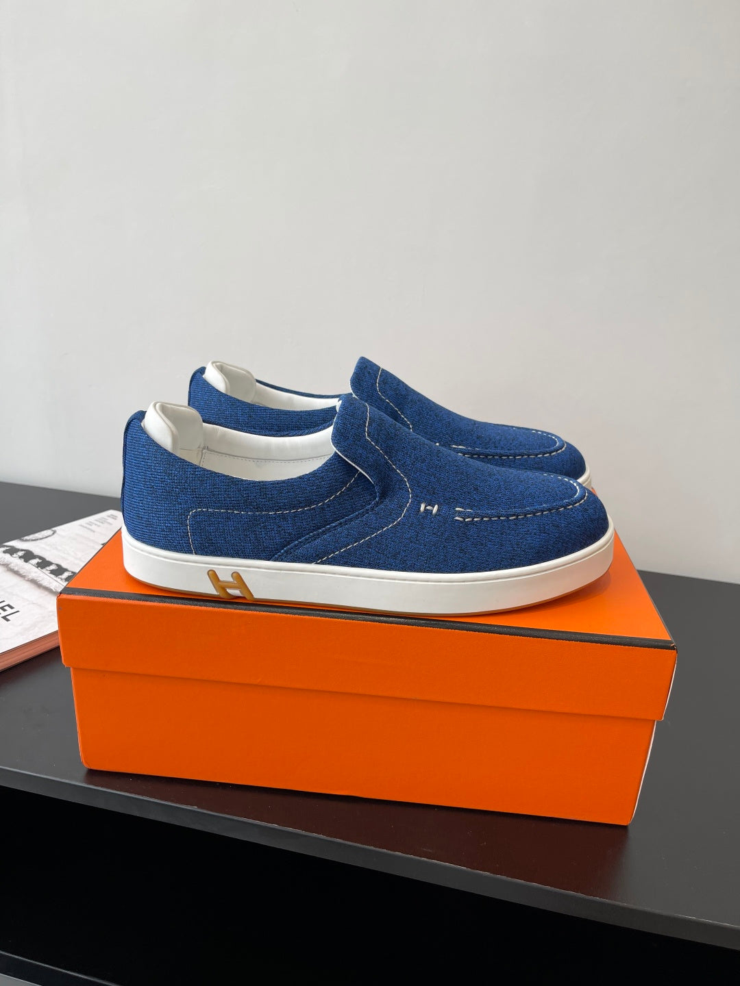 Pair of blue denim slip-on loafers with white soles on display.