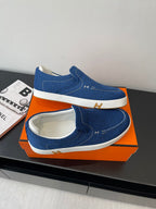 Blue denim slip-on loafers with white rubber soles and stitched upper edges.