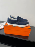 Hermes women's navy denim slip-on sneakers with white sole, side seams visible