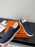 Hermes women's navy denim slip-on sneakers, angled view with white outsole