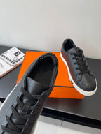 Close-up of black lace-up sneakers with padded tongue and white outsole trim.