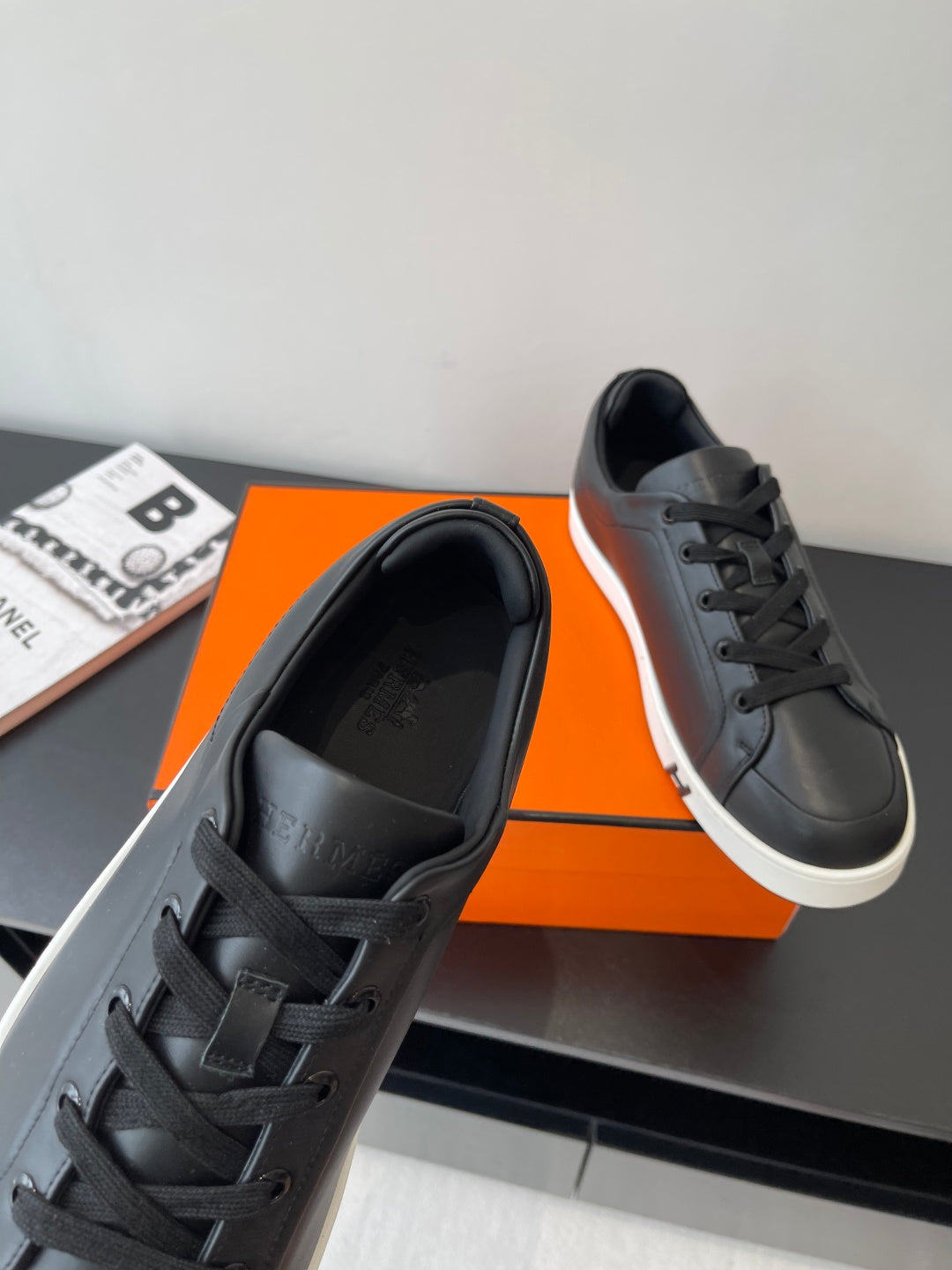 Close-up of black lace-up sneakers with padded tongue and white outsole trim.