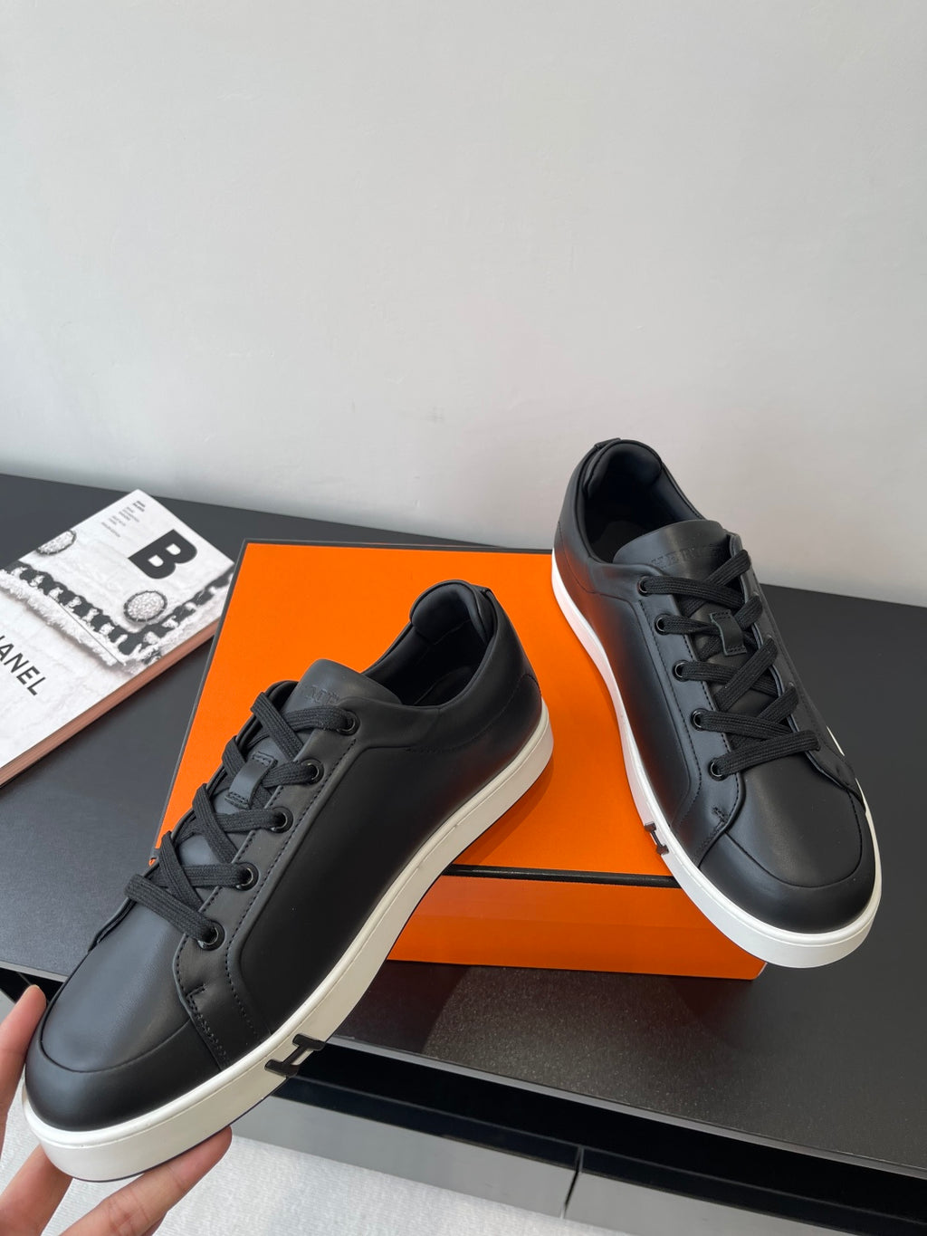 Black leather low-top sneakers with lace-up design and white sole, shown at side angle.