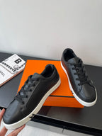 Black leather low-top sneakers with lace-up design and white sole, shown at side angle.