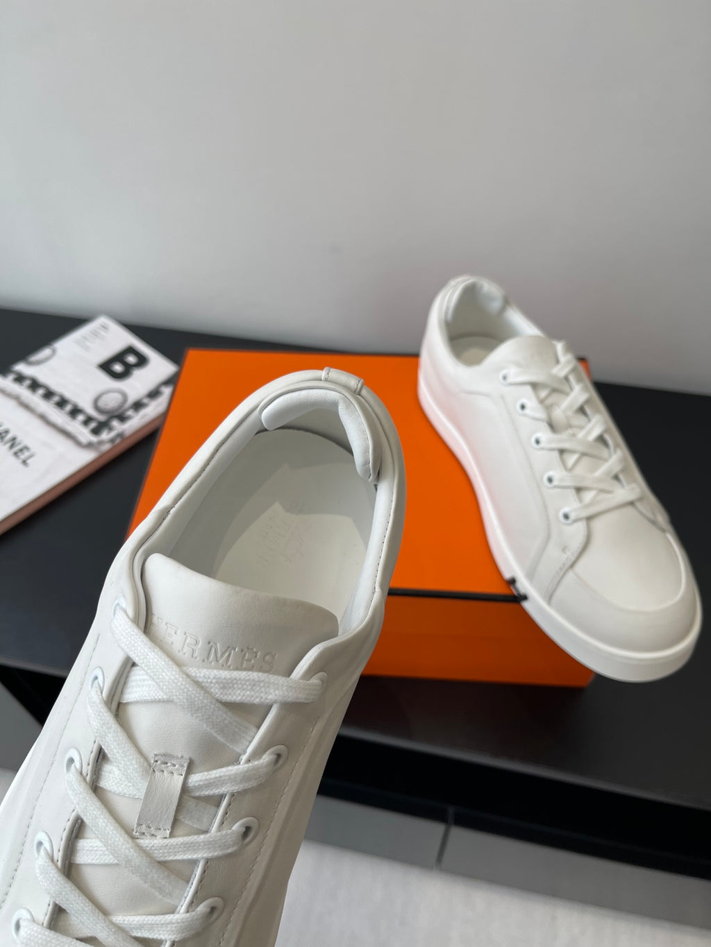 Hermes women’s white lace-up sneaker, close-up of padded tongue and stitching