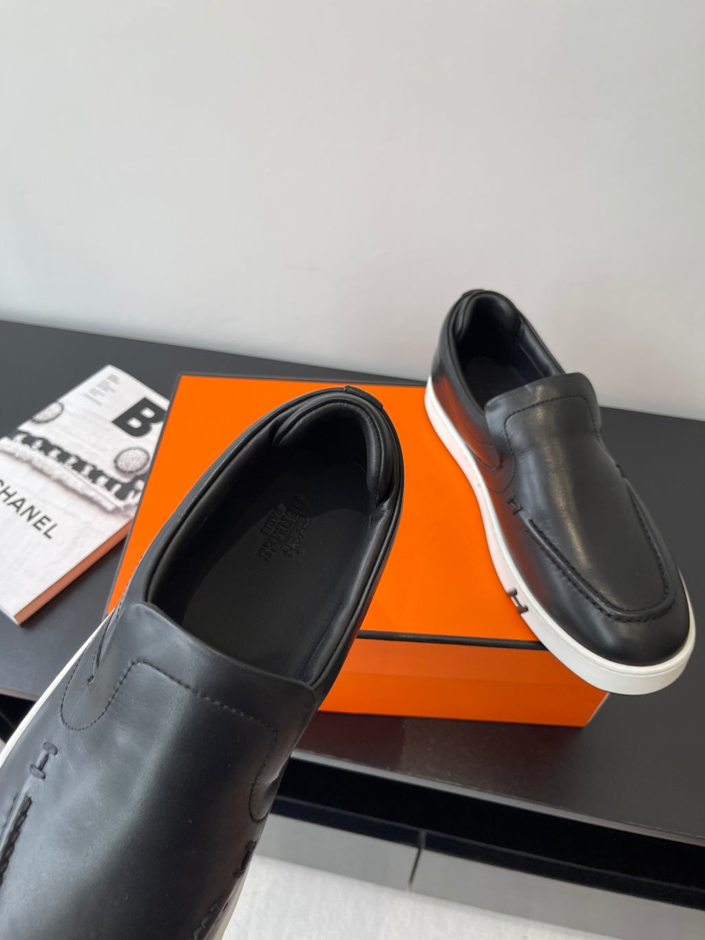 Black leather slip-on loafers with stitched upper and white rubber sole