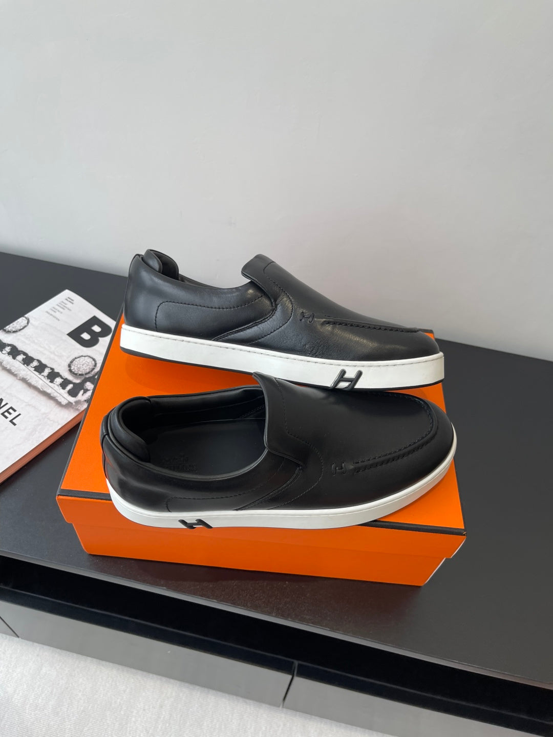 Black leather slip-on loafers with white midsole and side logo detail