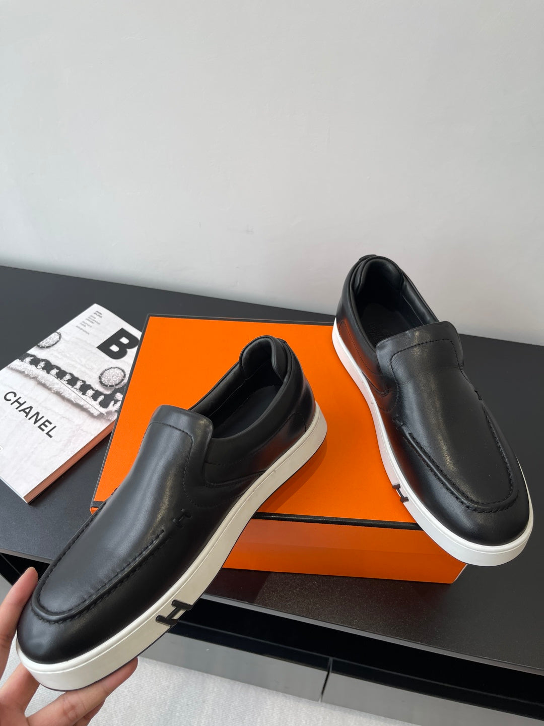 Pair of black leather slip-on loafers with white sole and side strap detail