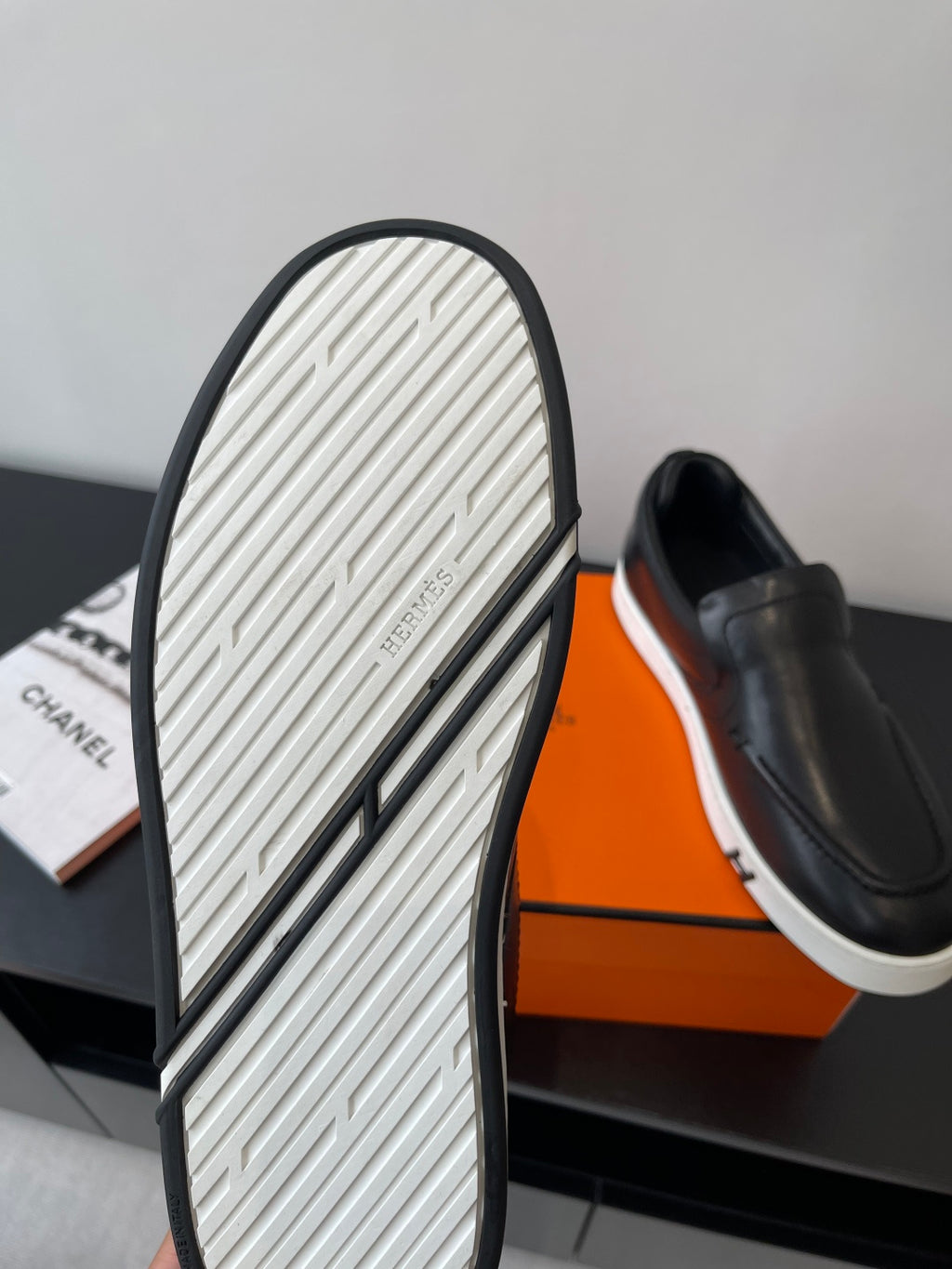 Outsole view of black slip-on loafer with textured tread and white stripe