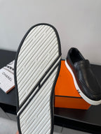 Outsole view of black slip-on loafer with textured tread and white stripe