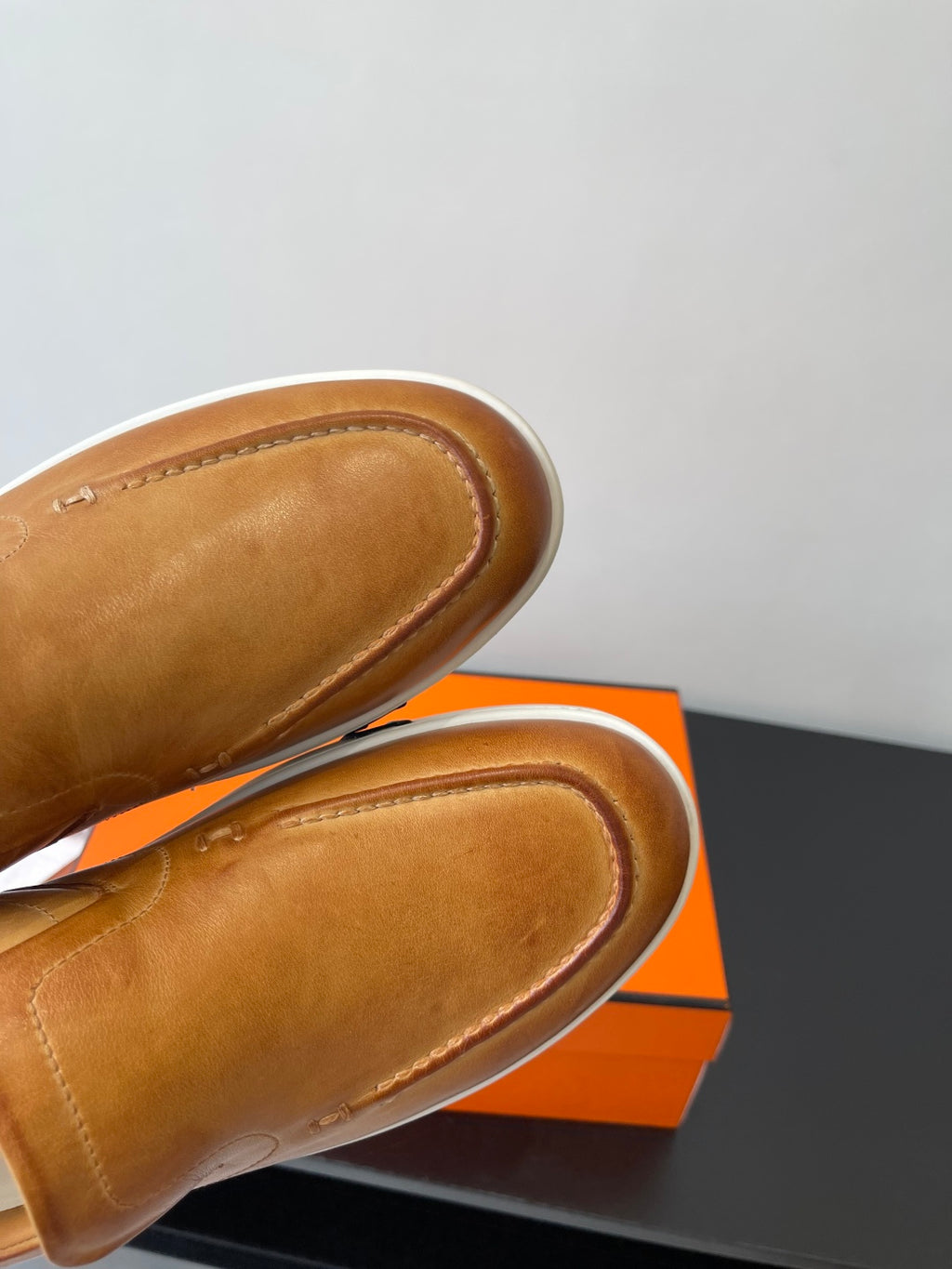 Close-up of brown leather loafer fronts with rounded moc toe stitching.