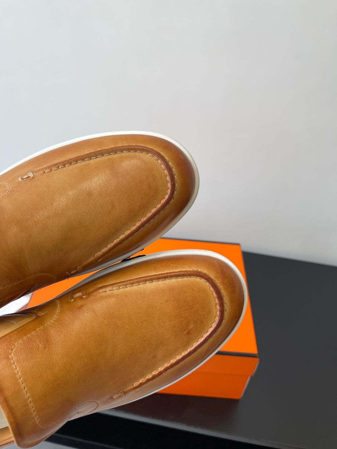 Close-up of brown leather loafer fronts with rounded moc toe stitching.