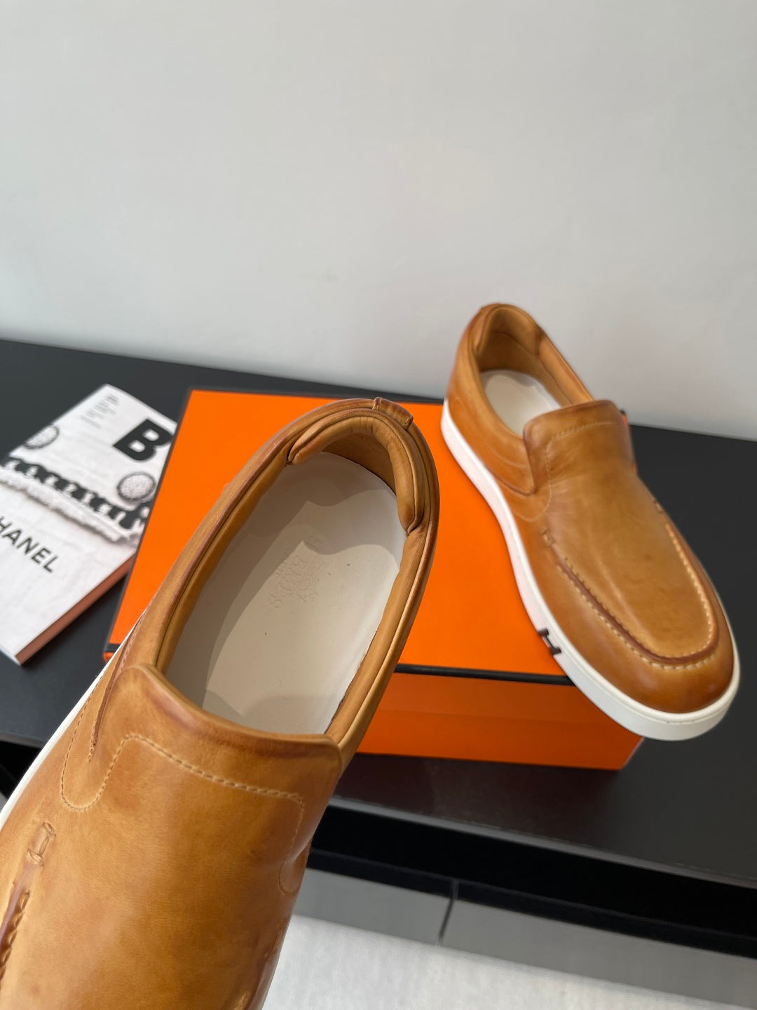 Brown leather slip-on loafers; one shows open interior and smooth lining.