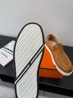 Bottom view of brown slip-on loafers with textured tread on white sidewall.