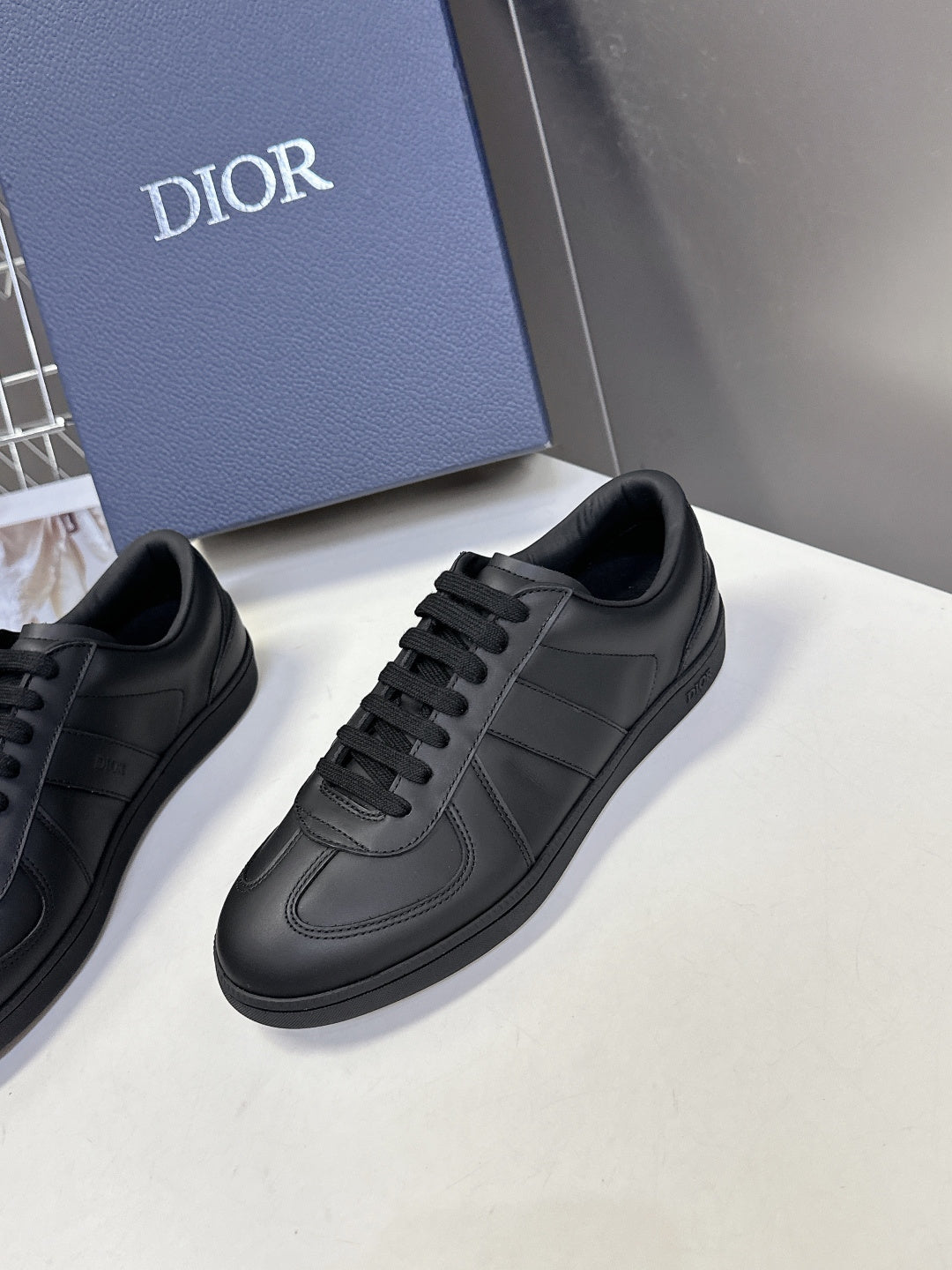 Black lace-up sneakers, side view with tonal stitching and cup sole