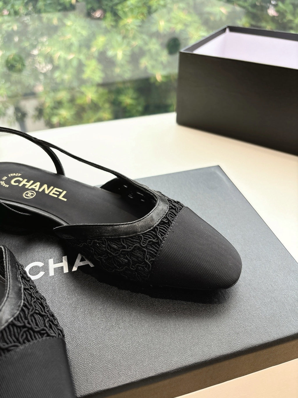 Close-up of black Chanel women's slingback shoes, textured toe and CHANEL branding