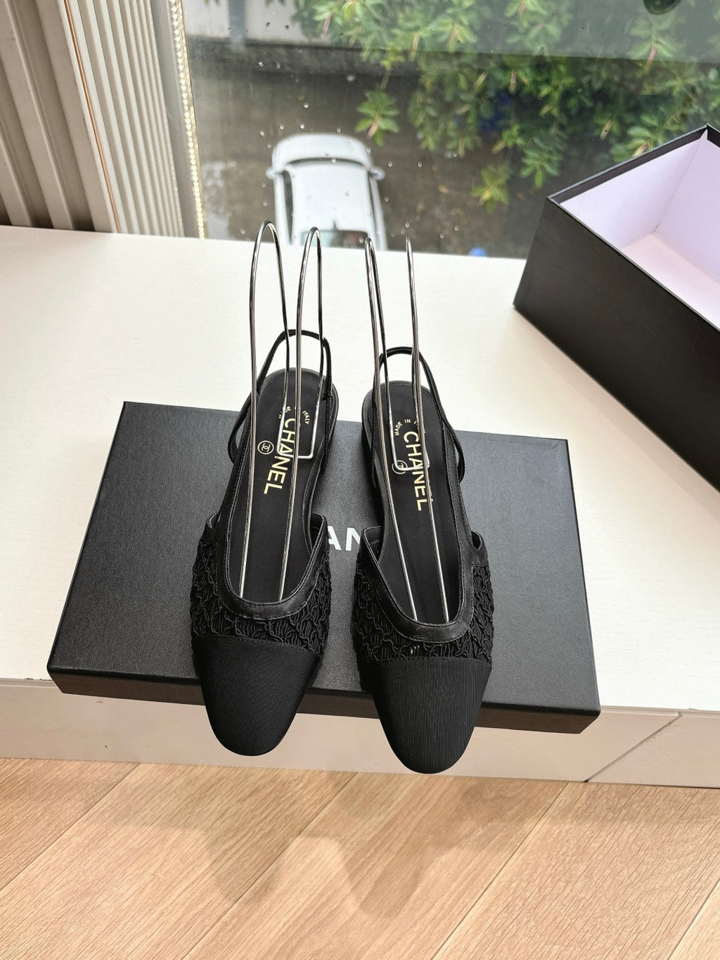 Pair of black Chanel women's slingback shoes on a dark box, slim pointed shape