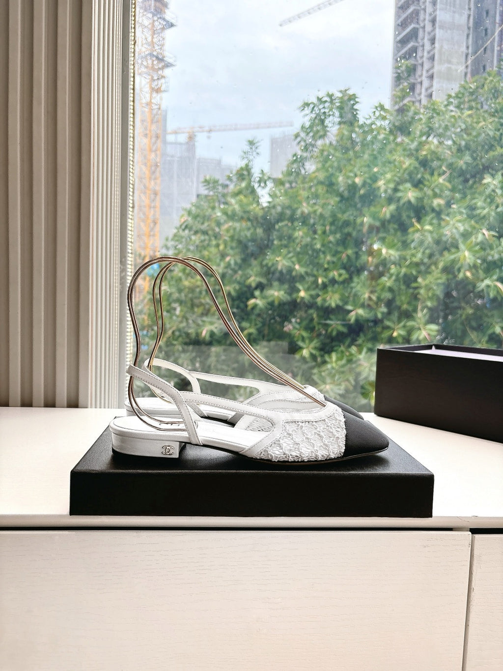 Chanel ladies slingback shoe on black display box, white textured upper with black heel