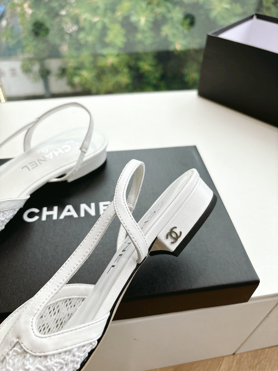 Chanel slingback shoes, white upper and black heel, side view on black box