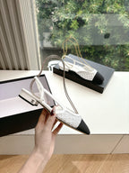 Chanel ladies slingback pump, white textured upper with black toe and heel, held in hand