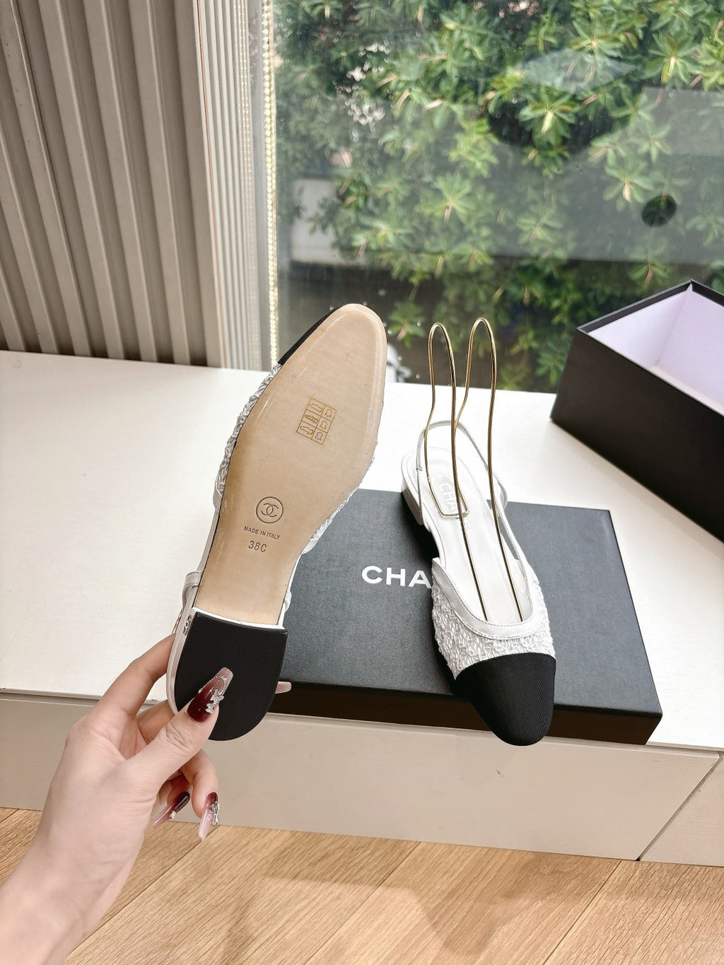 Chanel ladies slingback shoes, sole view with white upper and black heel, on black box