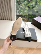 Chanel ladies slingback shoes, sole view with white upper and black heel, on black box