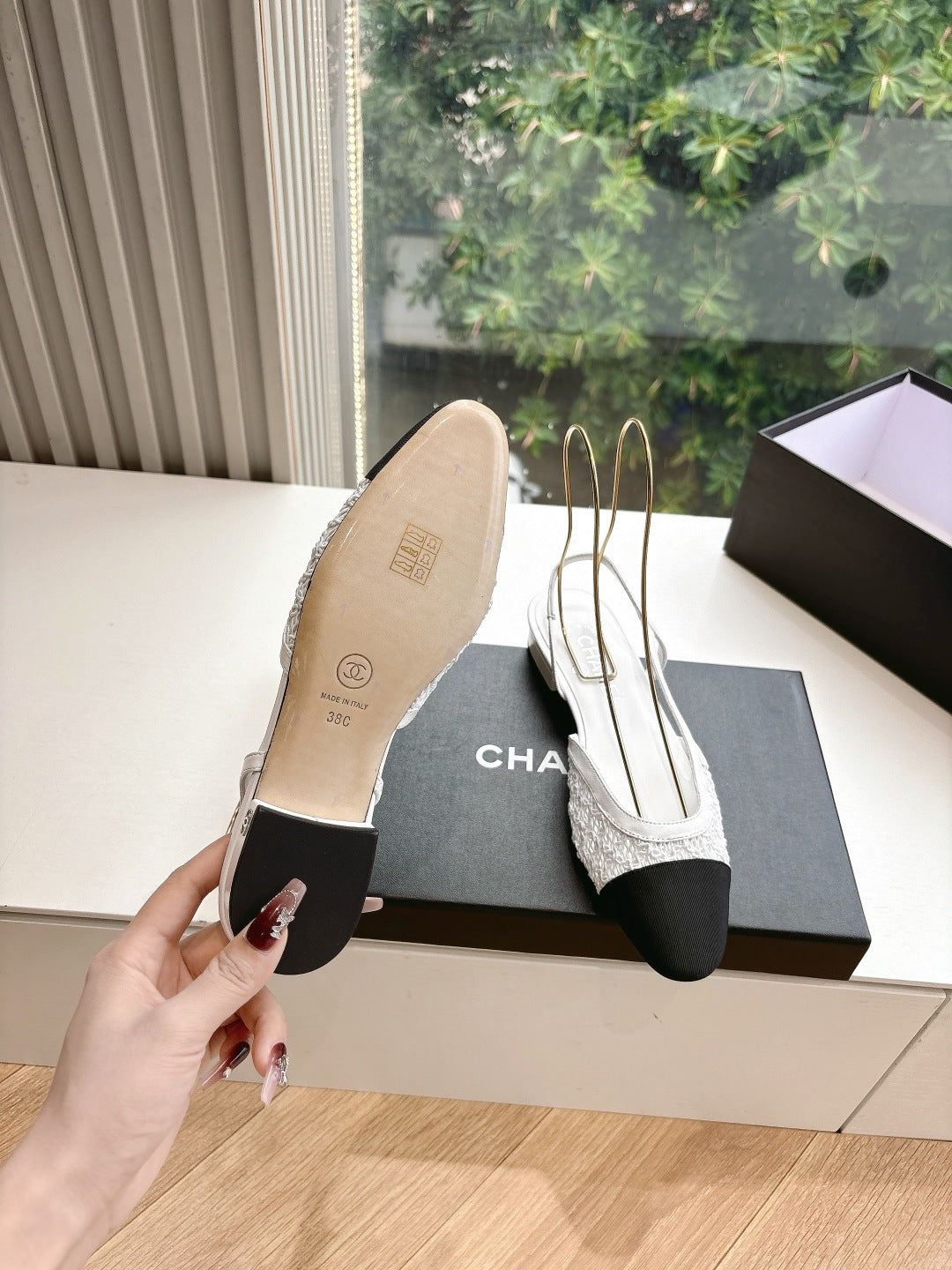 Chanel ladies slingback shoes, sole view with white upper and black heel, on black box