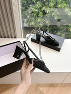 Black Chanel slingback heels, pointed-toe style, shown in hand