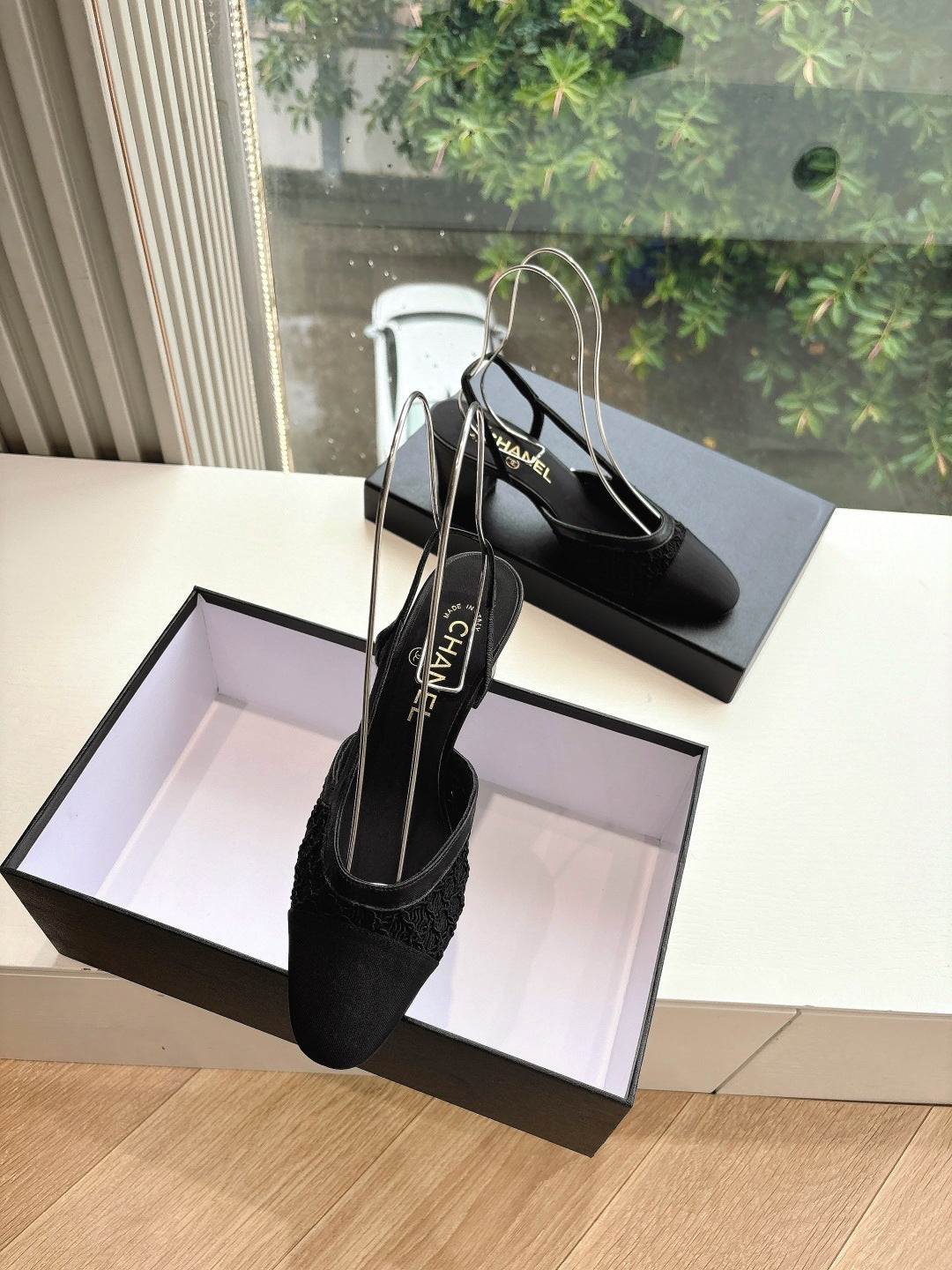 Black Chanel slingback heels with textured upper, on display box