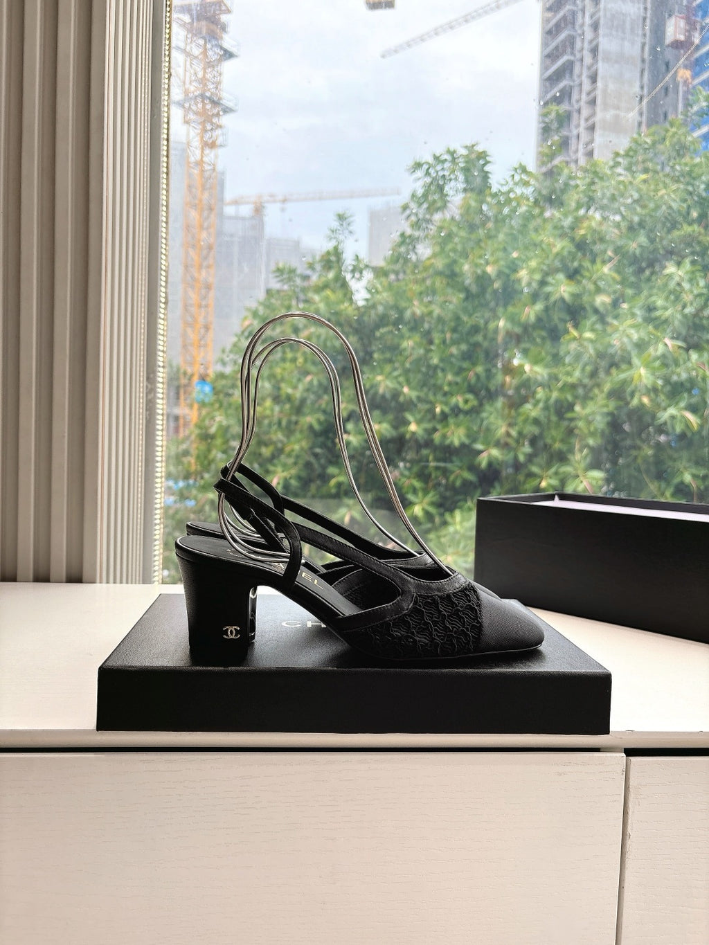 Black Chanel slingback shoes with pointed toe and slim heels, standing on box
