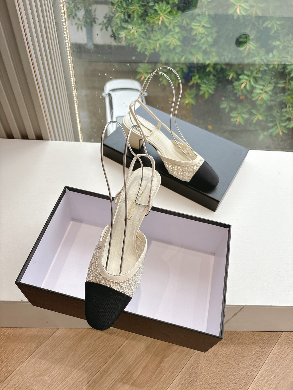 Two-tone women’s slingback heels on black box, black toe caps and textured beige upper