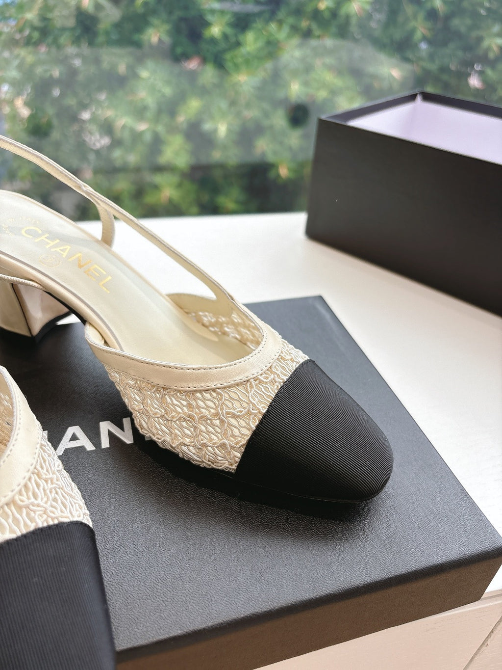 Close-up of two-tone women’s slingback heel: textured beige strap and black toe