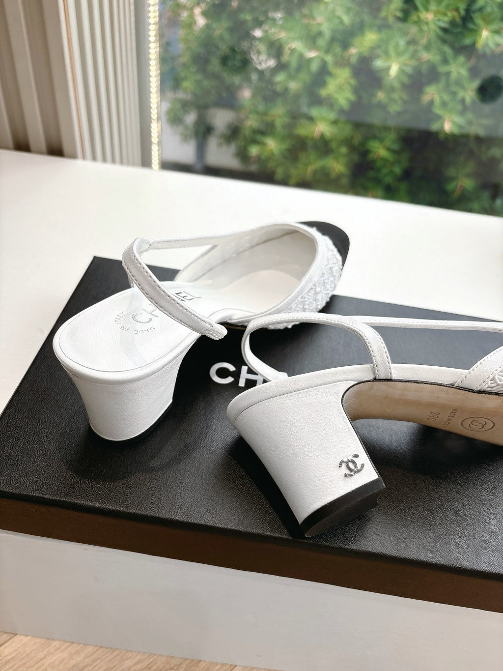 Two-tone slingback heels with textured white straps and dark toe on display boxes
