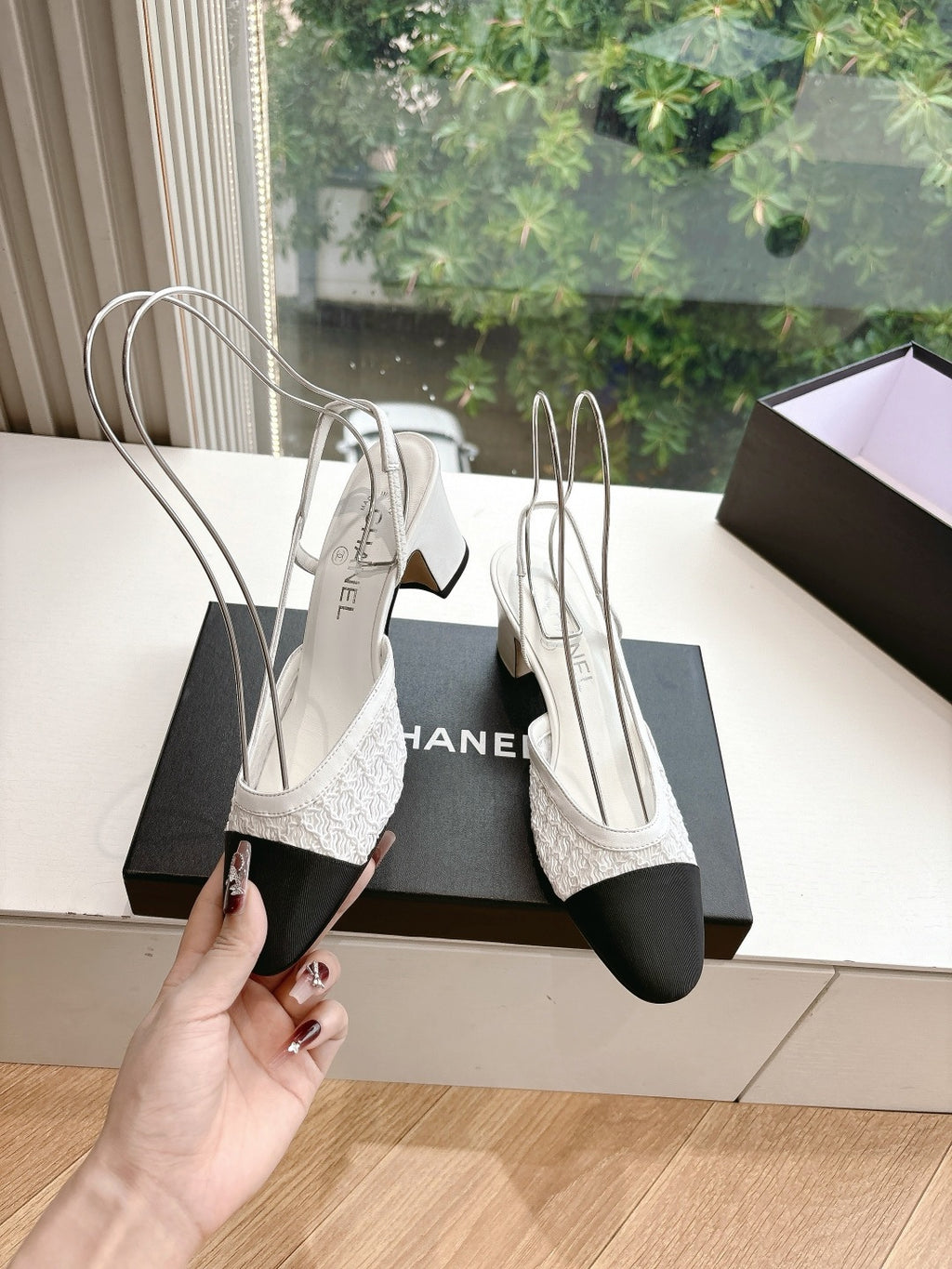 Two-tone slingback heels with textured white upper and dark toe, held near box