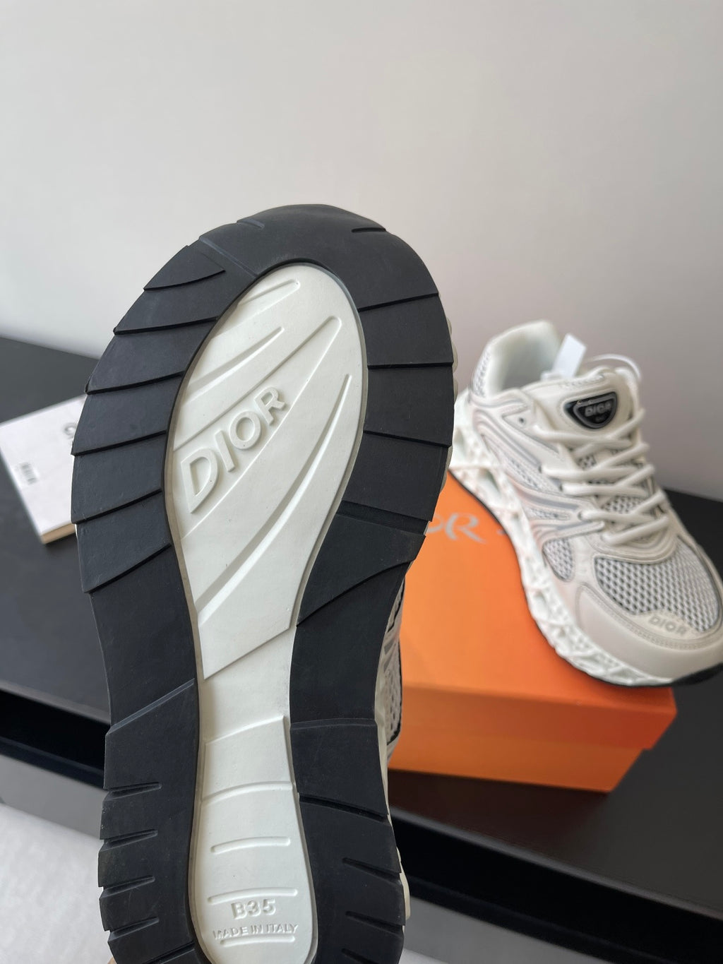 White sneaker outsole with dark rubber tread and Dior logo on heel