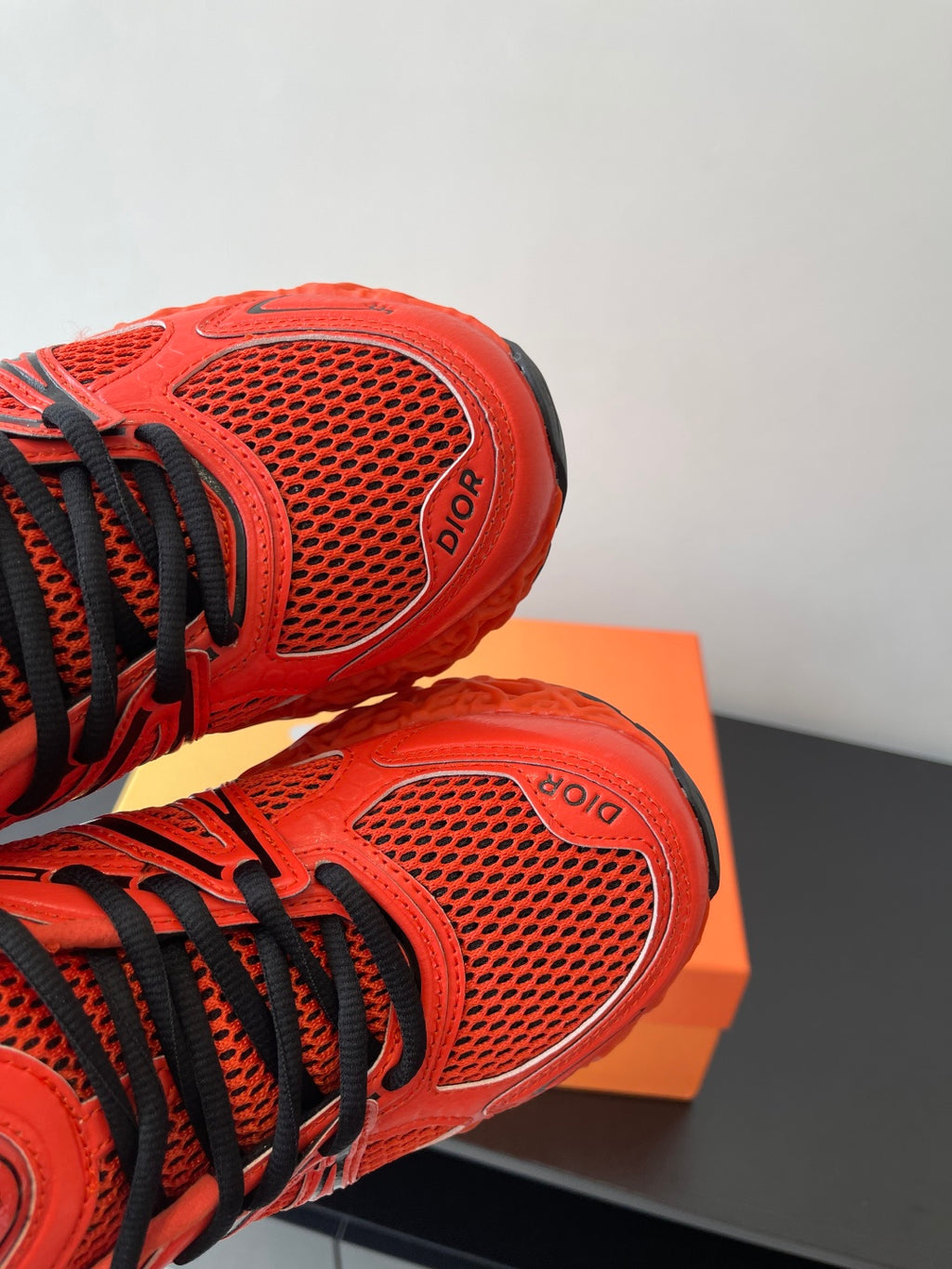 Red Dior ladies sneakers close-up of perforated mesh toe and side logo