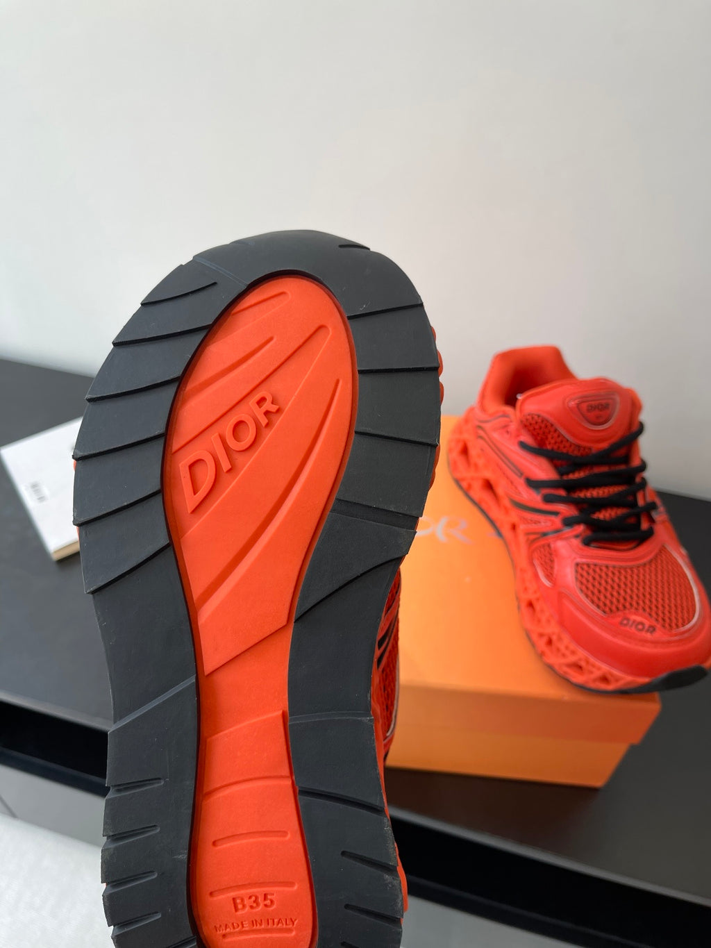 Red Dior sneaker outsole tread with black midsole and logo