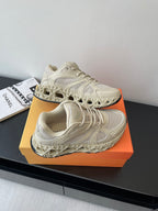 Cream lace-up sneaker with thick tread sole, mesh upper and embossed panel pattern