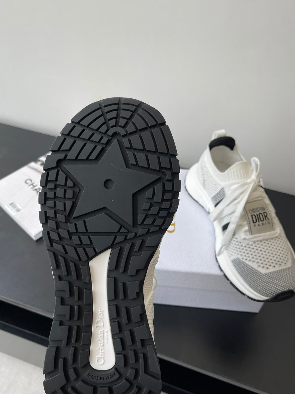 White sneakers with black tread outsole, lace-up design, Dior logo on heel