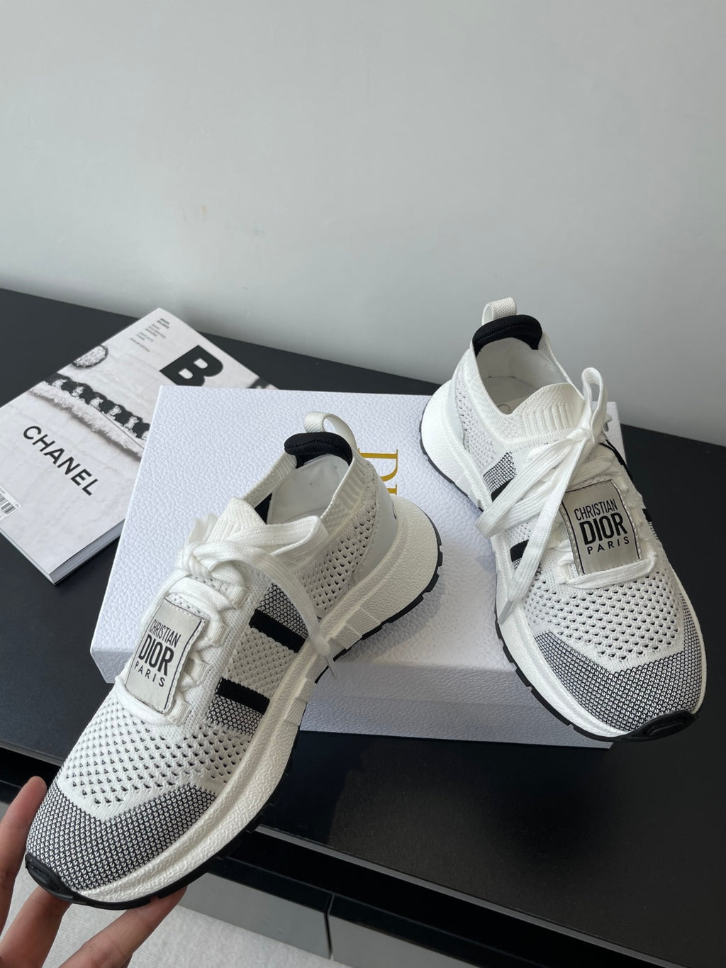 White mesh sneaker pair with black side stripe and white laces, Dior label on tongue
