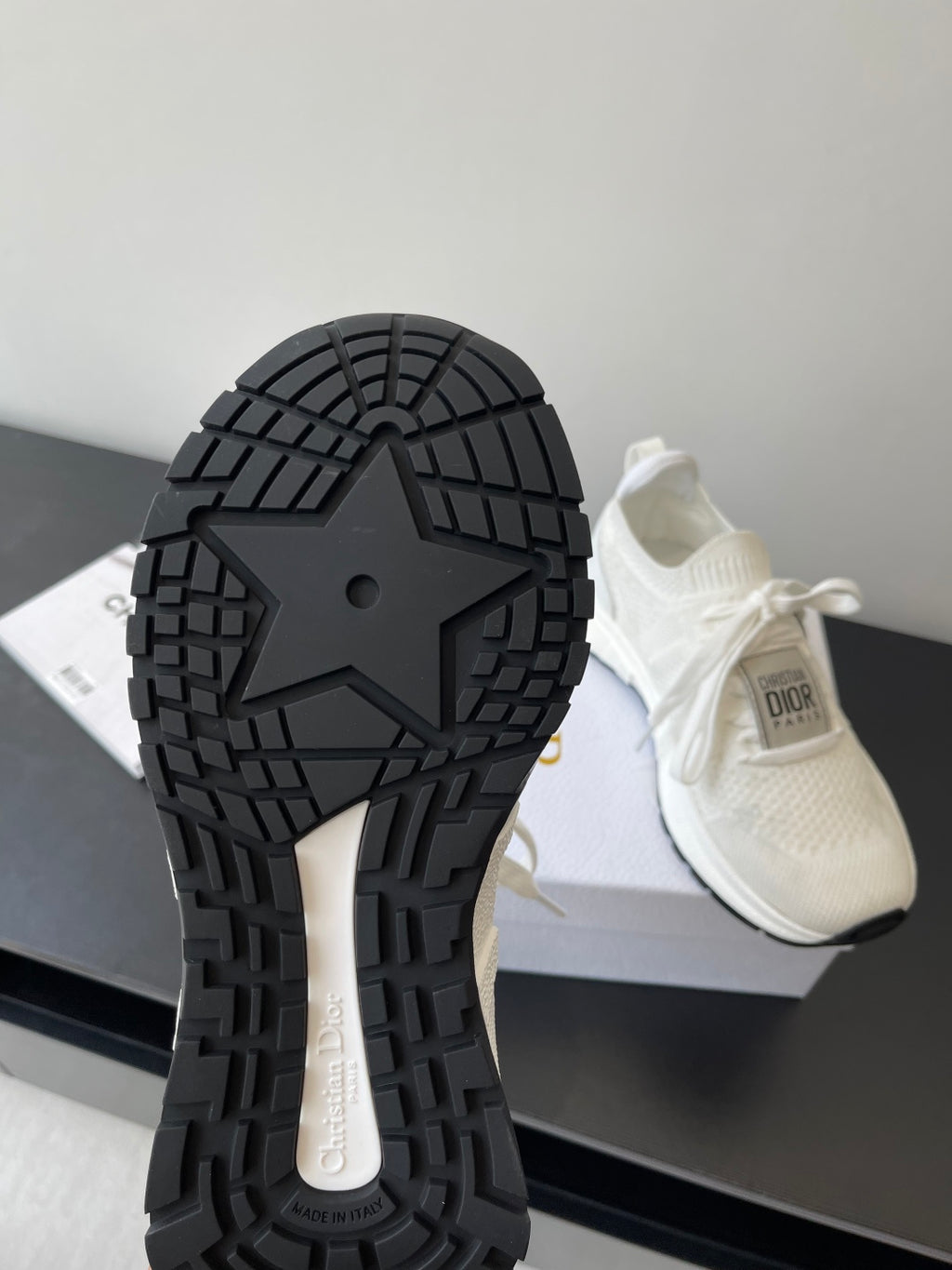 White Dior sneakers showing textured tread outsole and chunky rubber sole