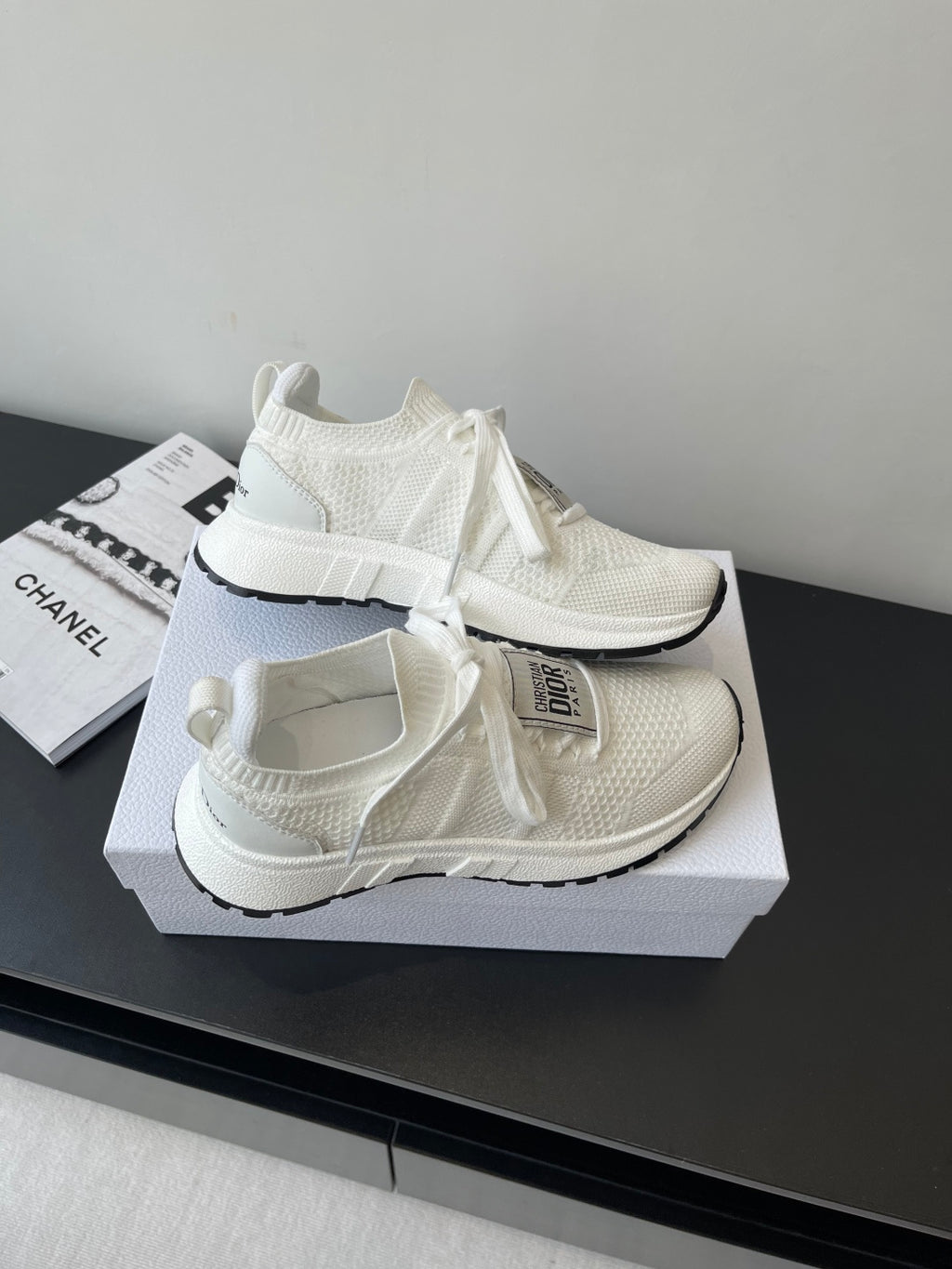 White Dior knit sneakers with lace ties and thick sole, angled on display