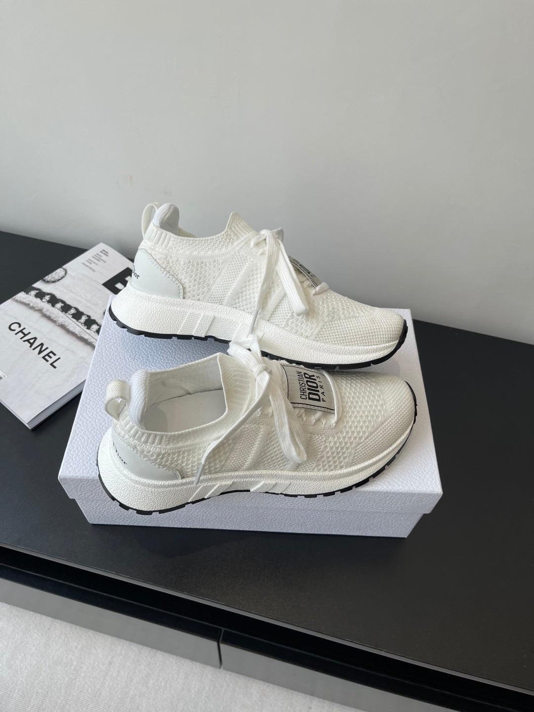 White Dior knit sneakers with lace ties and thick sole, angled on display