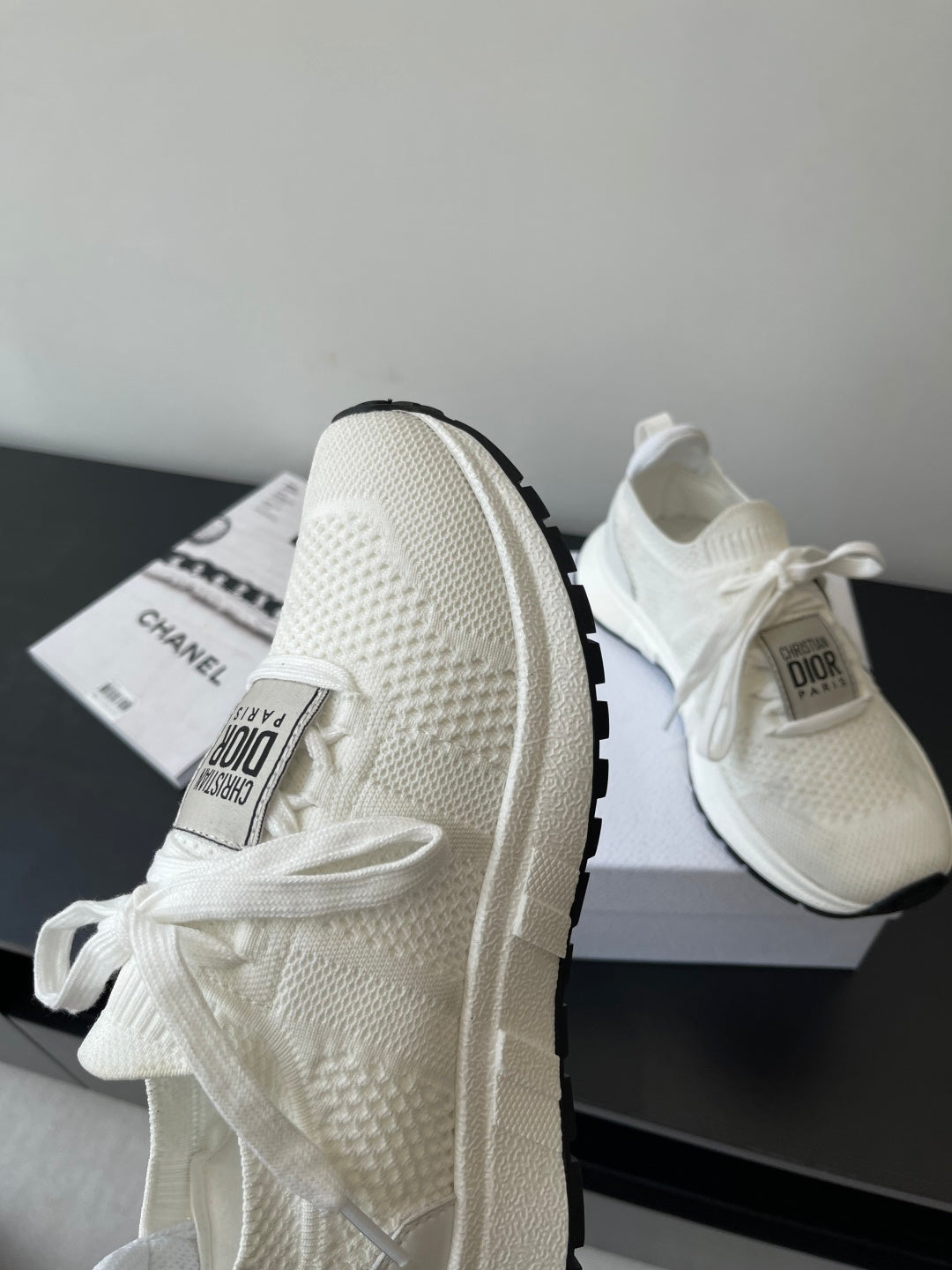 White Dior sneakers viewed from the side, showing lace ties and thick sole