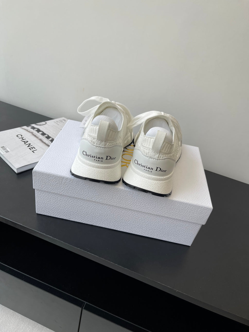 White Dior sneakers pair with lace ties on a box; rear and side profile