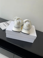 White Dior sneakers pair with lace ties on a box; rear and side profile