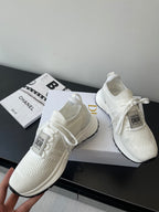 Pair of white Dior knit sneakers on display, with lace ties and cushioned sole